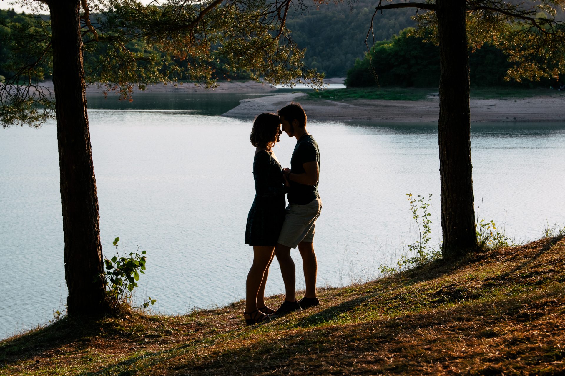 Photo représentant un couple, photo réalisé en contre jour, avec un lac en arrière plan